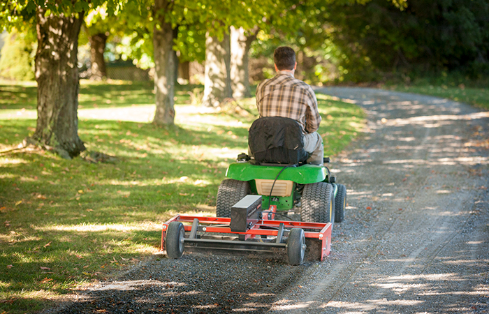 A power grader in use on a driveway.