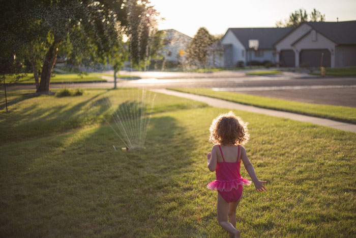 child playing by sprinkler