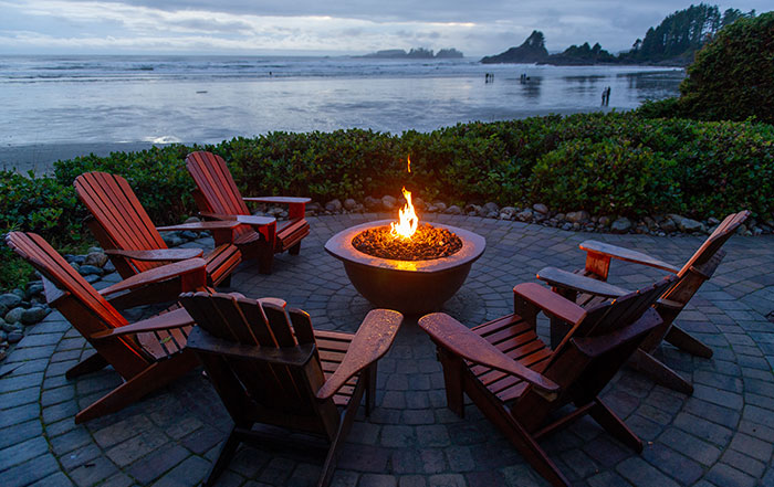 Adirondak chairs around a firepit, overlooking the ocean.