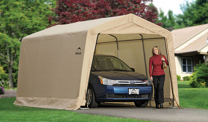 A woman exits a portable carport, in which is parked a blue sedan.