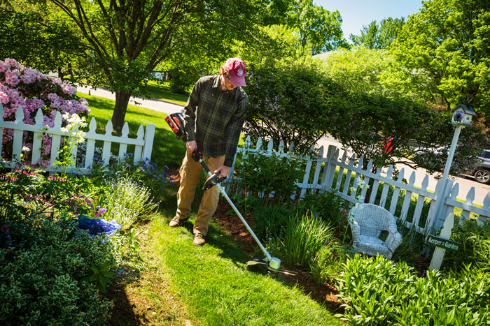 male using string trimmer in back yard