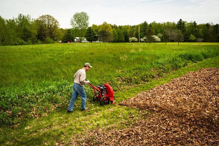 male using walk behind blower