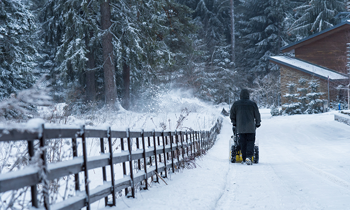 Person using a snowblower on winter driveway