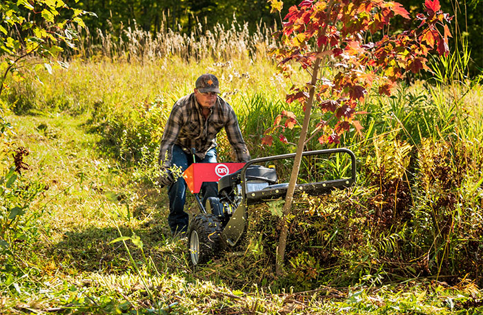 Using a field and brush mower to mow tall grass and saplings.