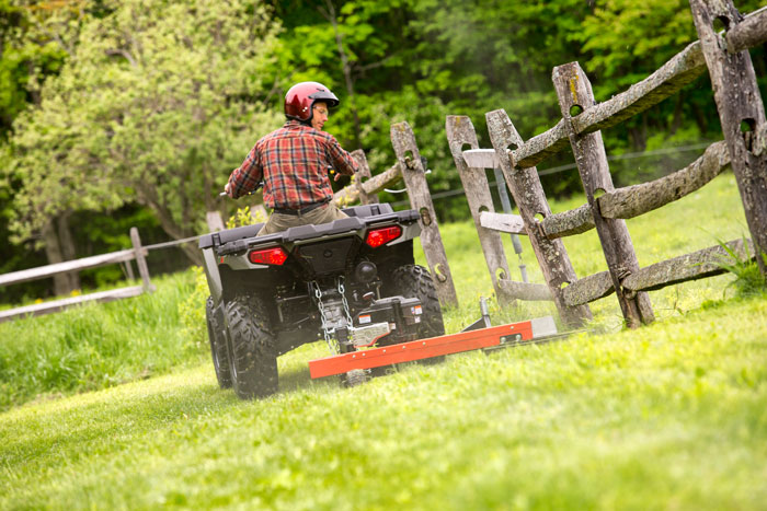 Trimming a fence line with a tow-behind string trimmer. 