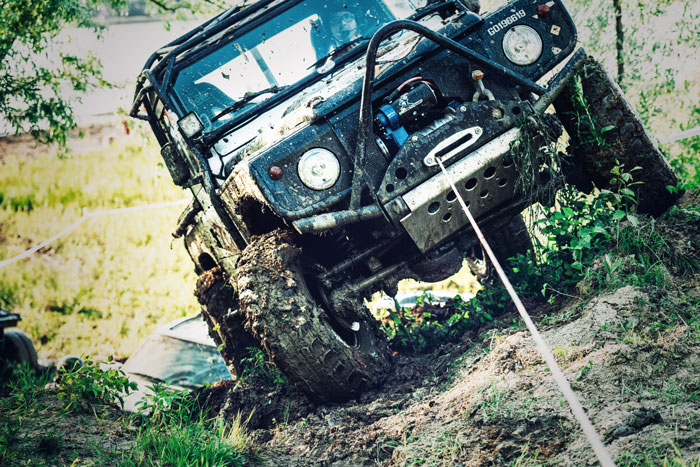 An ATV equipped with a winch pulls itself out of a bad spot.