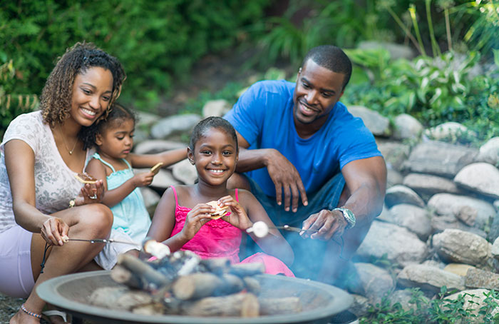 A family enjoys s'mores around a fire pit.