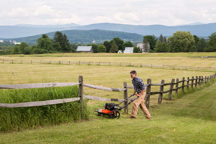 male using trimmer mower in field