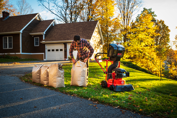 Male putting filled paper leaf bags out by curb