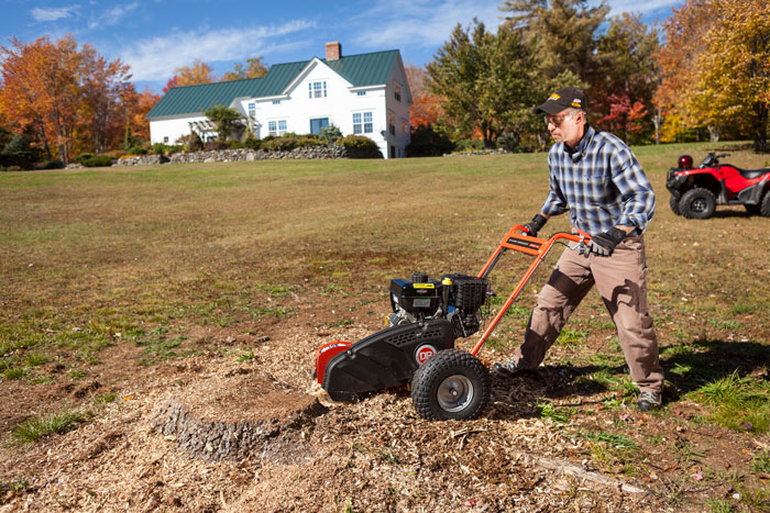 A man uses a DR stump grinder to remove a stump from his yard