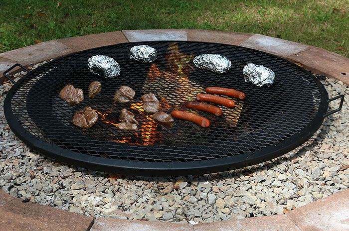 Hot dogs and burgers cooking on a fire pit grill.