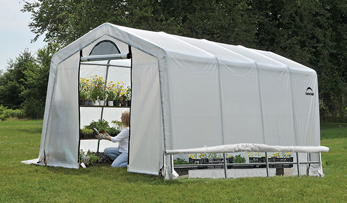 A woman tends to plants in a greenhouse.