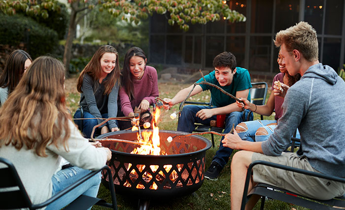 A group of teens roast marshmallows over a fire