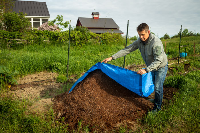 Man spreading tarp over firewood